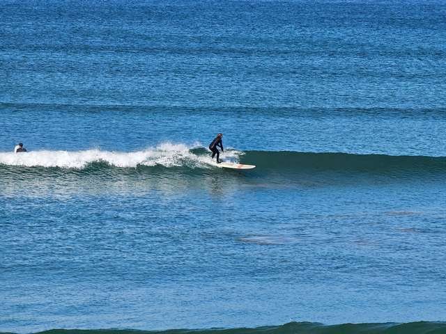 Longboarder riding a hip high wave in front of the shop